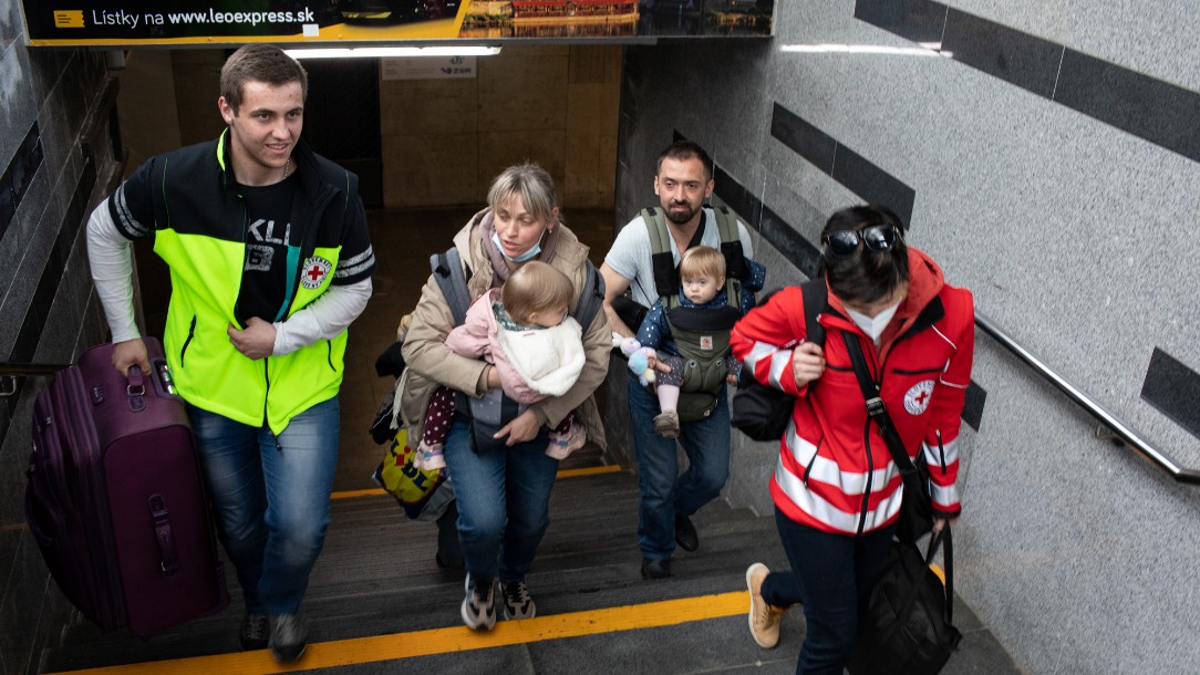 Two volunteers from the Slovak Red Cross help a woman and man with two children and lots of luggage on their arrival in Slovakia from Ukraine