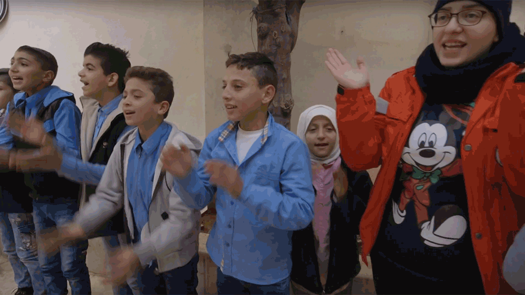 Children laugh as they sing nursery rhymes under the direction of a group of dedicated young volunteers from the Syrian Arab Red Crescent.