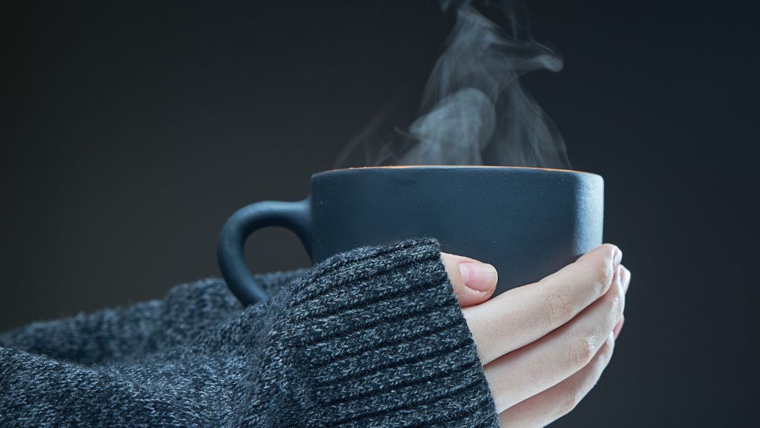 Someone warming their hands on a cup of tea