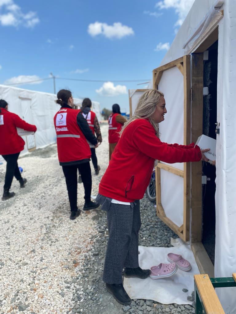 A Turkish Red Crescent volunteer gives a family living in makeshift shelter after the Turkey-Syria earthquake a support package.