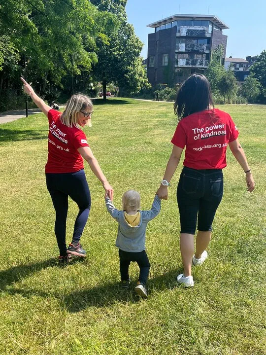 two women and a toddler hold hands on a charity walk for the British Red Cross