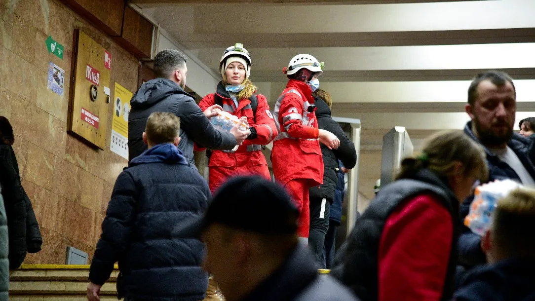 A woman wearing Red Cross clothing looks at the camera as she helps to distribute aid in a subway station in Kyiv, Ukraine
