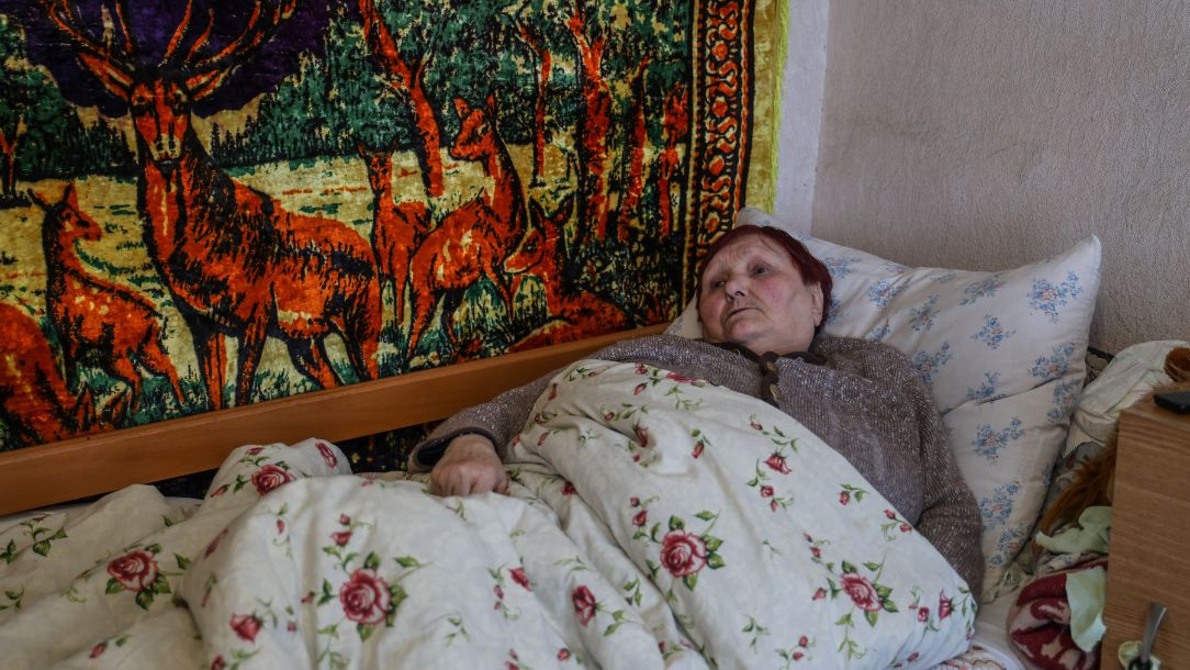 Pensioner Valentyna lies in bed in Ukraine after a stroke.