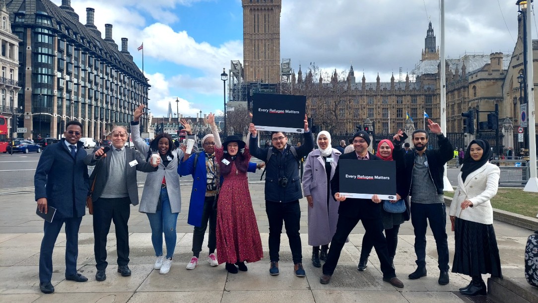 Members of the VOICES network stand outside Parliament holding 'Every Refugee Matters' signs