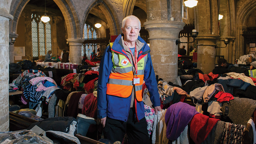 Volunteer at a donation centre surrounded by donated clothes.