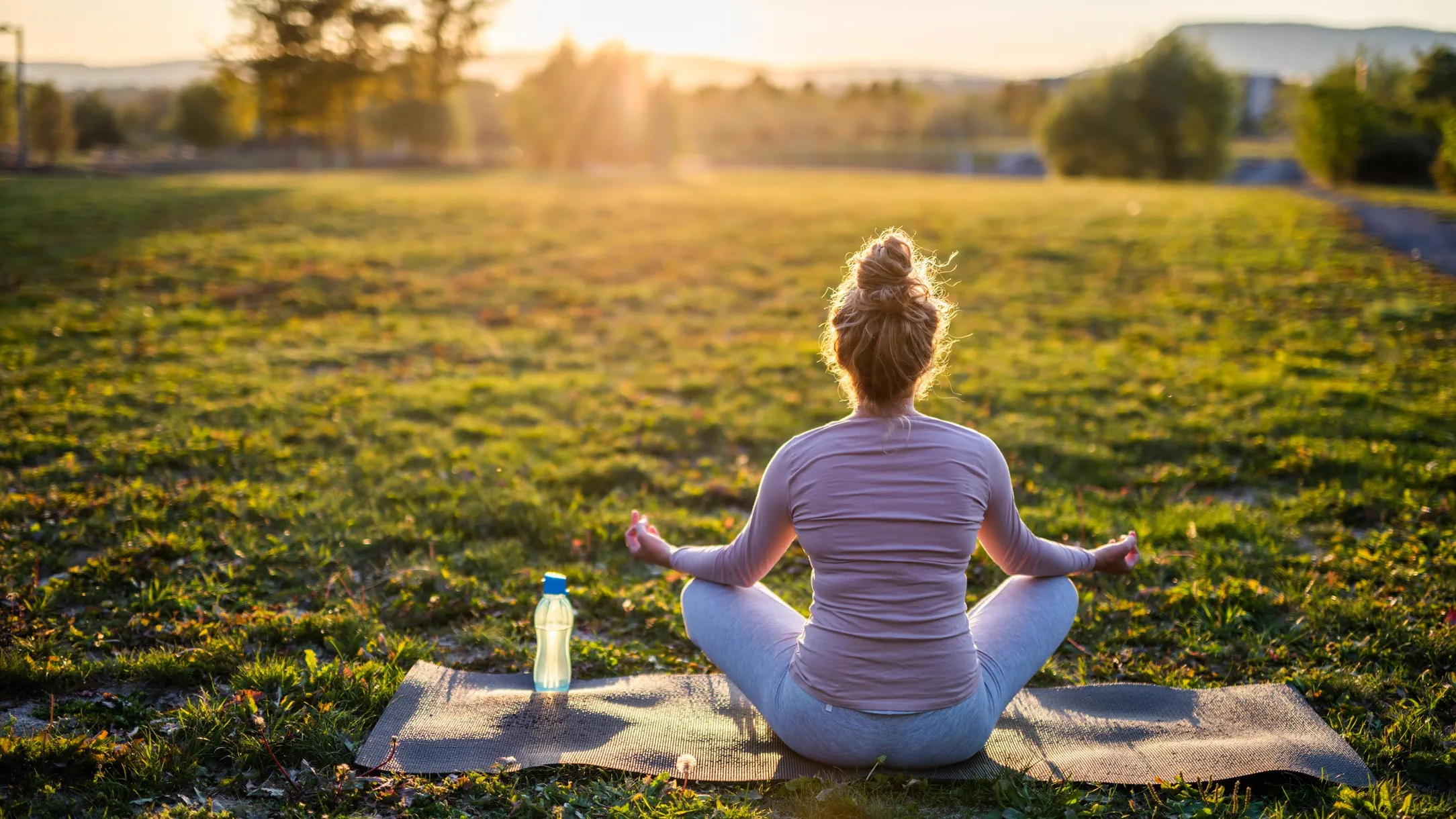 Woman meditates outside as the sun rises in the morning