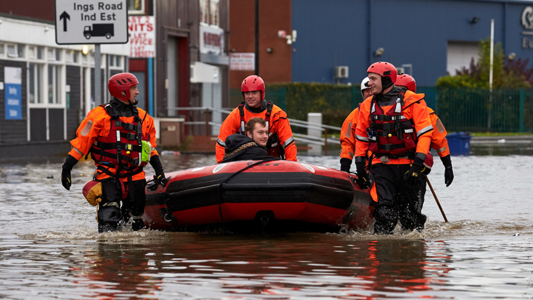 Volunteers pull a man in a raft through a flooded street in the UK.
