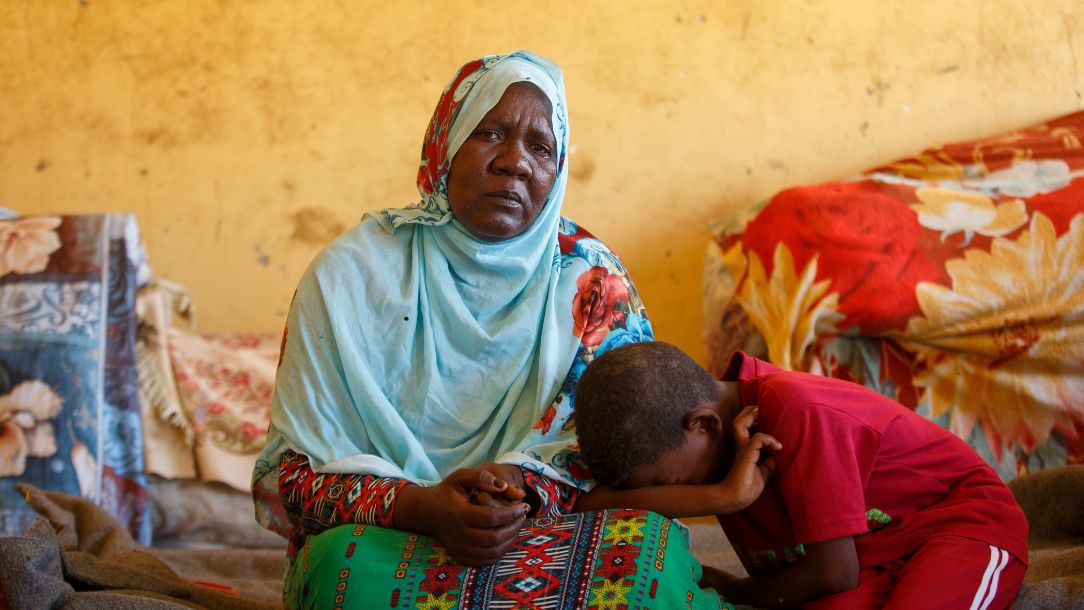 A Sudanese woman and her crying son in temporary shelter after fleeing conflict in Sudan.