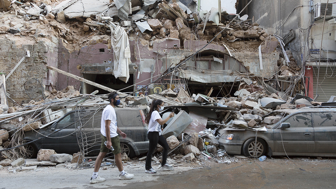 Two people walk past the devastating aftermath of the enormous explosion in Beirut.