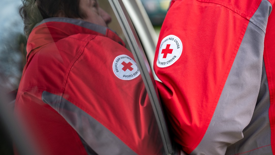 Close up of an emergency response volunteer's uniform showing the British Red Cross logo. 