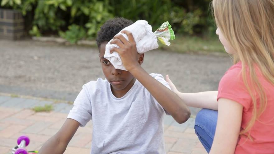 Young boy holds an ice pack to his head.