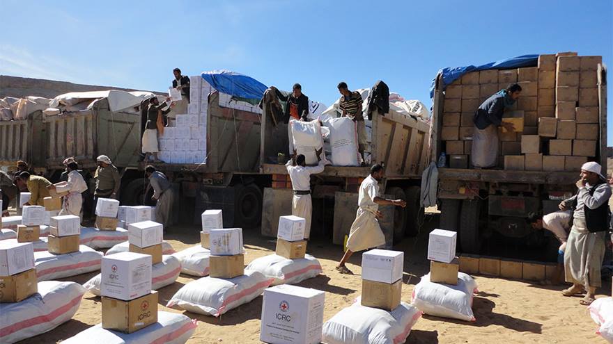 Group of adults unload humanitarian aid from trucks
