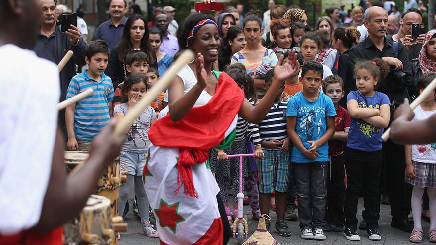 Woman dances in traditional cultural clothing in front of a crowd.