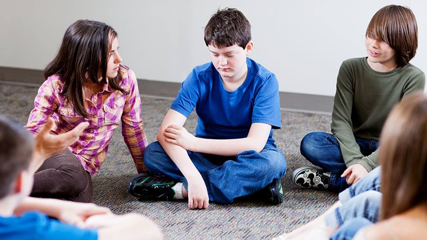 Group of young teenagers holding a discussion in a circle.