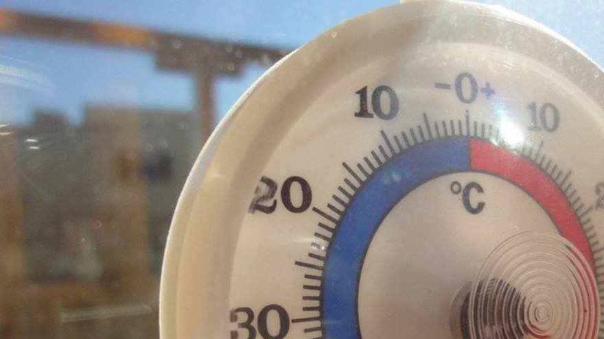 A thermostat in a window during a blazing hot day.