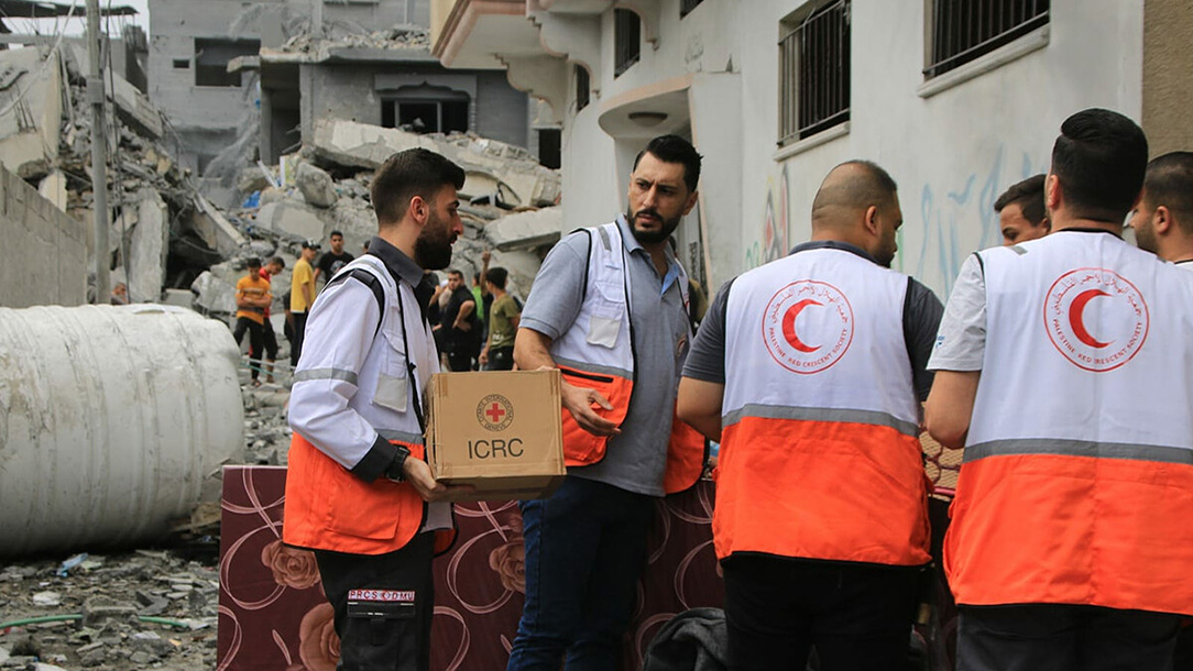 Palestinian Red Crescent staff and volunteers distribute aid deliveries in Gaza.