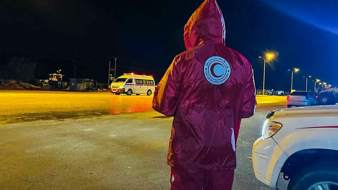 Libyan Red Crescent worker stands in a car park at night.