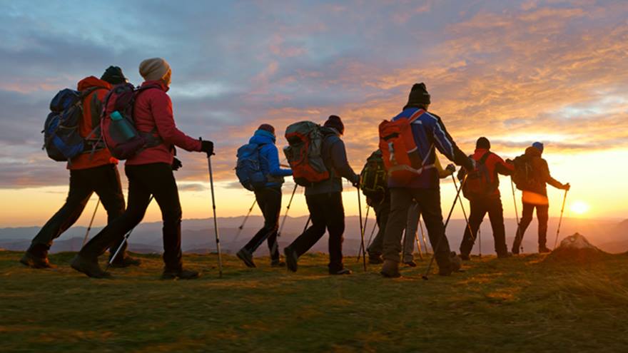 A group of hikers walking at sunset.