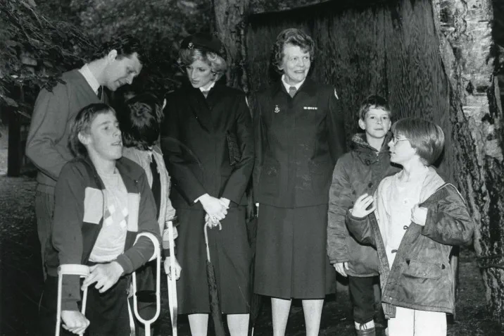 Princess Diana stands with a group of volunteers and children at a British Red Cross camp. 