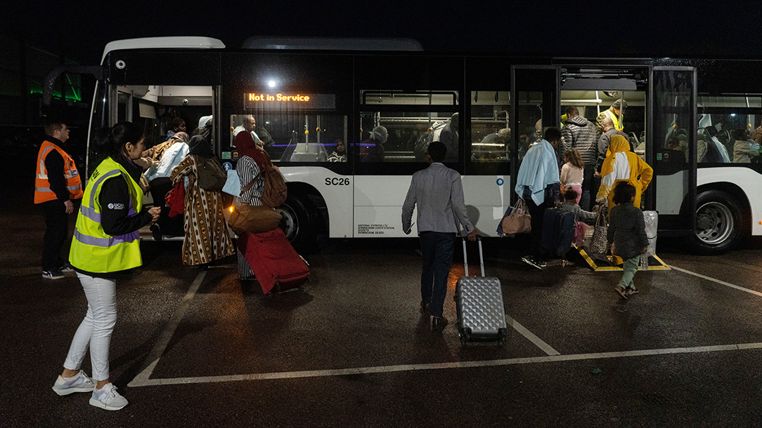 Sudanese evacuees board buses at airport.