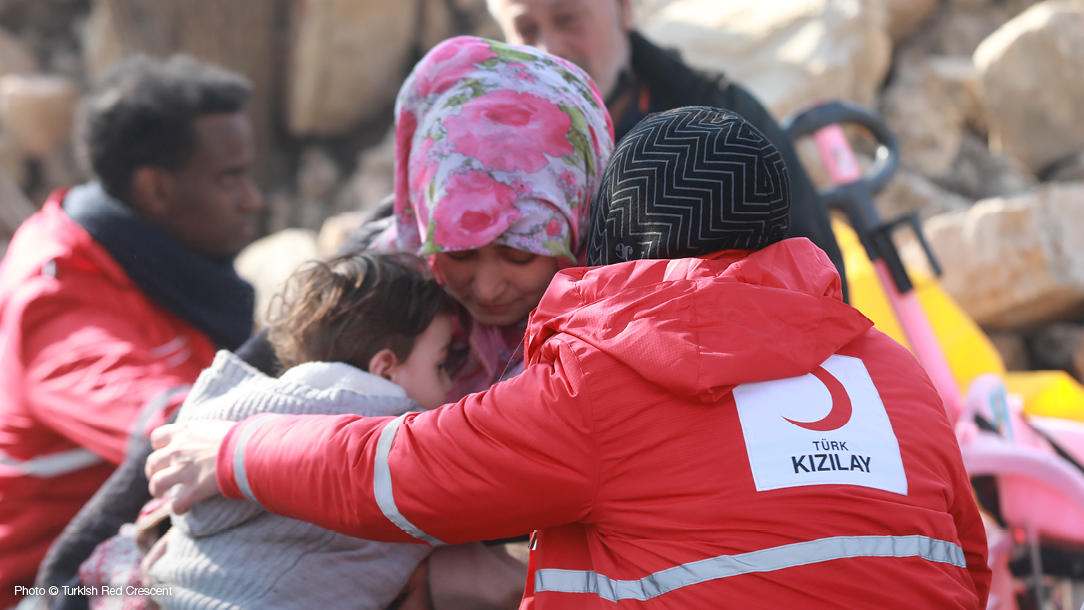 A member of the Turkish Red Crescent  consoles a woman and her child following the February 2023 earthquakes in Turkiye and Syria