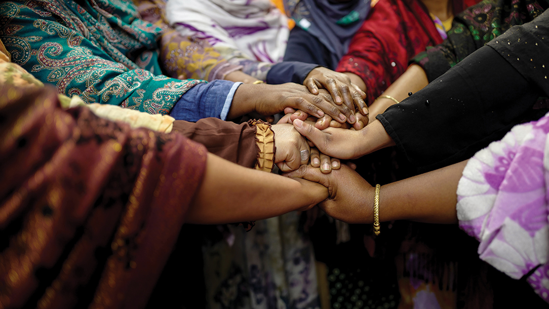 Group of women gather their hands together in a sign of unity